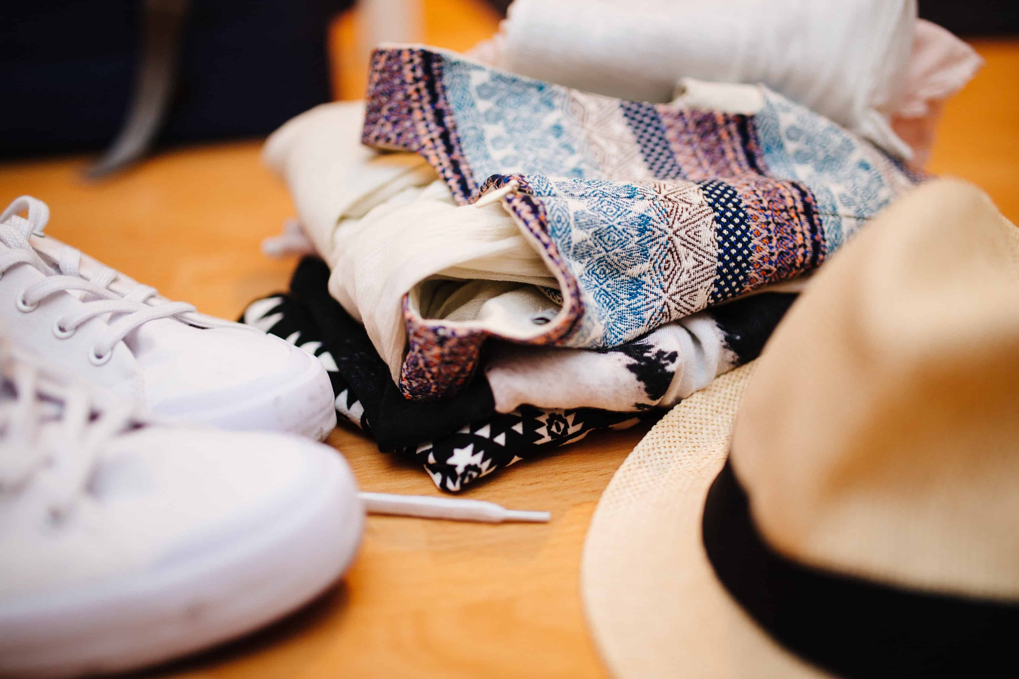 Clothes, trainers and hat on light wood table