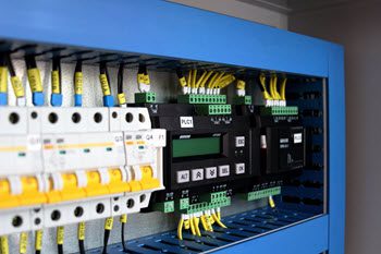 PLC maintenance technician inspecting a programmable logic controller panel