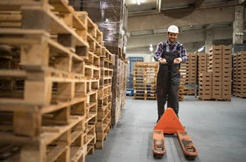 Electric and manual pallet jacks lined up in a warehouse aisle ready for a maintenance check