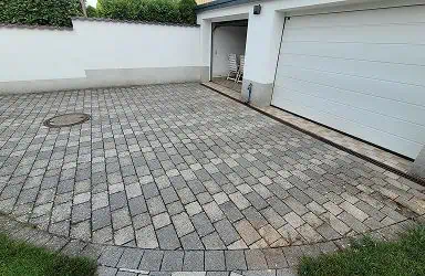 Gereinigte Pflasterfläche einer Einfahrt. Steinreinigung im Außenbereich als Leistung. Vorher Nachher Effekt der Reinigung von Steinen.