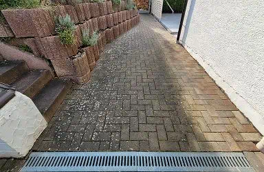 Vorher/Nachher: Vermooste Pflasterfläche gereinigt. Die dunkle Einfahrt erstrahlt durch professionelle Reinigung. Jetzt strahlt der Stein!