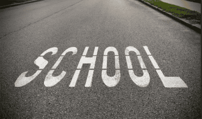 School zone warning sign on a road near school grounds