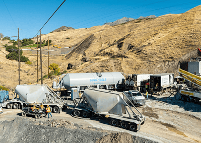 A western mountain slope with heavy construction grouting equipment at a landing pad.