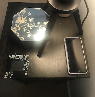 Black nightstand with a mobile phone, coaster and jewelry box