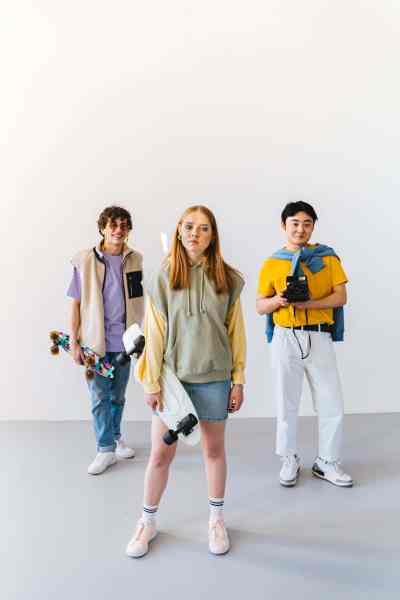 a woman holding a skateboard standing between two men