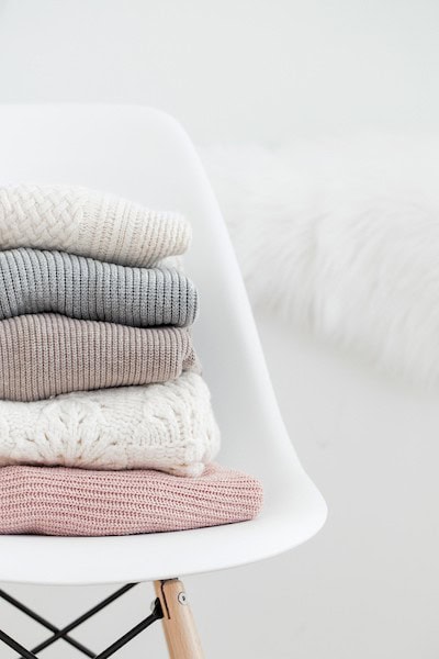 folded knit sweaters in white chair