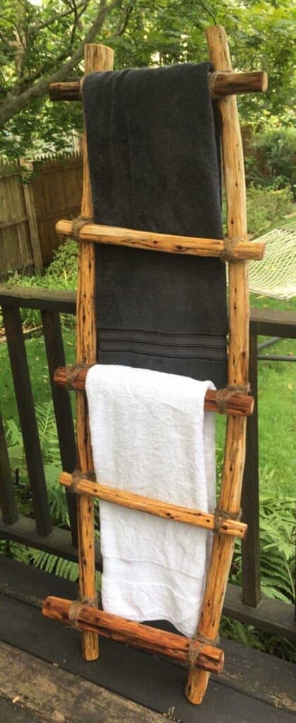 Blanket ladder leaning against a deck railing in a backyard.