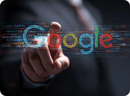 Uma mão em um terno aponta para a palavra "Google" multicolorida, formada por pequenos textos e códigos em uma interface digital escura.