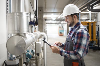 Un ouvrier d'entretien utilise un appareil mobile pour inspecter l'équipement avec eWorkOrders GMAO