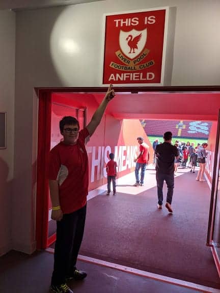 Boy on Liverpool F.C. Anfield Tour pointing at an Anfield sign.