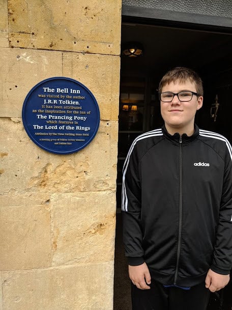 Teenage boy standing by J.R.R Tolkien The Bell Inn sign