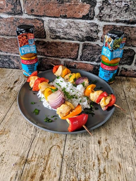 Kebabs and rice on a black plate on wooden surface