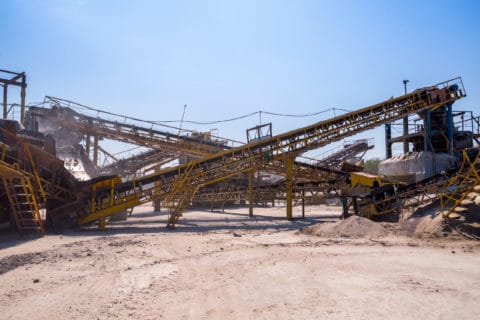 Active aggregate mining and crushing facility with conveyor systems and processing equipment at a quarry operation — industrial extraction site subject to air quality permitting, dust emissions compliance, and environmental regulatory consulting by EDGE Engineering.