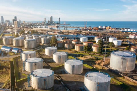 Aerial view of oil and gas terminal with steel storage tanks of oil and LPG petrochemical. Oil tank farm for gas, diesel and petroleum in a sea port near industrial plant and chemical refinery
