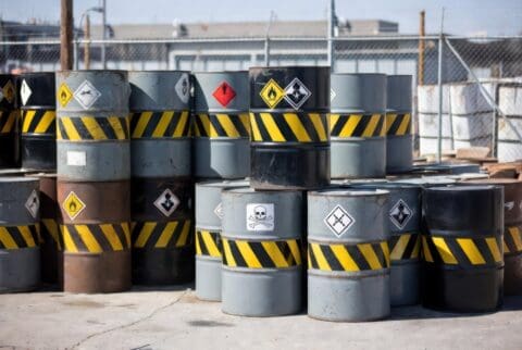 Industrial hazardous waste drums with warning labels at a storage facility