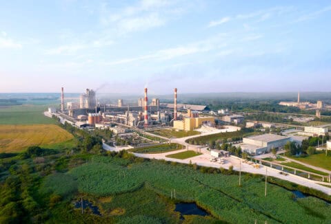 Aerial view of a large industrial chemical or manufacturing complex surrounded by green fields and tree buffers — major stationary source facility requiring air quality permitting, environmental impact assessment, and Clean Air Act regulatory compliance consulting by EDGE Engineering.