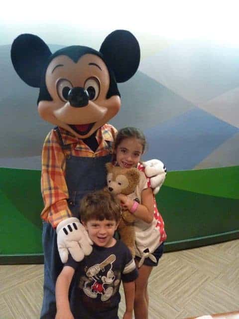 The kids pose with Mickey Mouse in his farmer outfit (Overalls and Plaid shirt) at the Garden Grill in Epcot