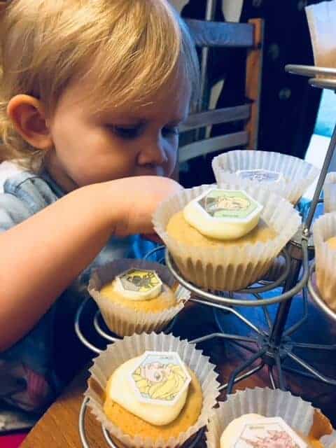 baby girl putting the toppers on the cupcakes
