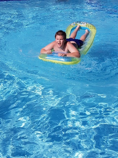 A young boy laying on a float in a swimming pool