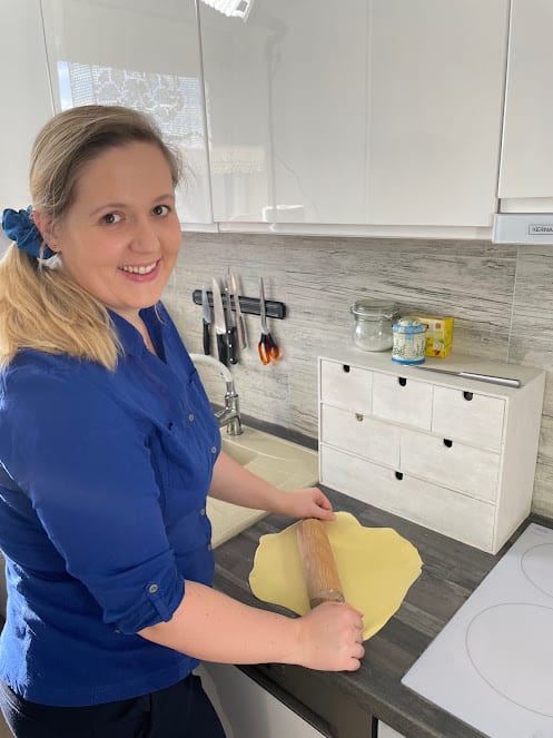 A woman in a blue shirt is preparing dough at home.