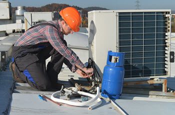 Technician servicing a commercial HVAC rooftop unit