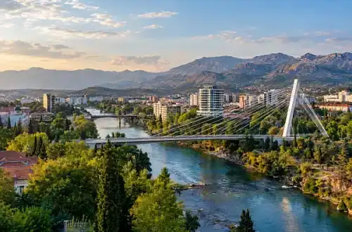 Panoramablick auf Podgorica mit der Millennium-Brücke über die Morača und den Bergen Montenegros im Hintergrund.