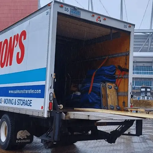 Salmon's Moving and Storage truck with open rear door showing moving equipment and supplies, professional moving company vehicle with website branding