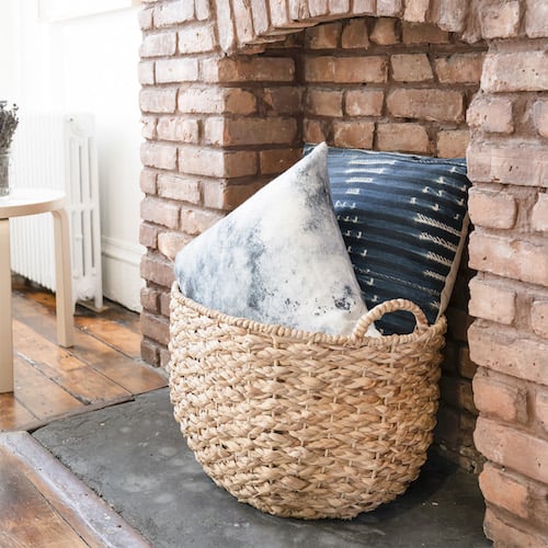 pillows in woven basket on non-functional fireplace hearth