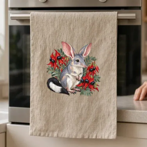Lifestyle photo of the Bilby Among Sturt Desert Peas Tea Towel being worn or used