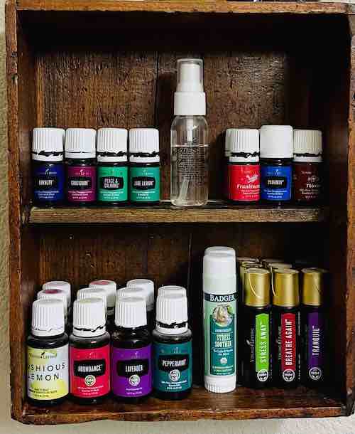 Essential oil bottles stored on a wooden shelving unit.