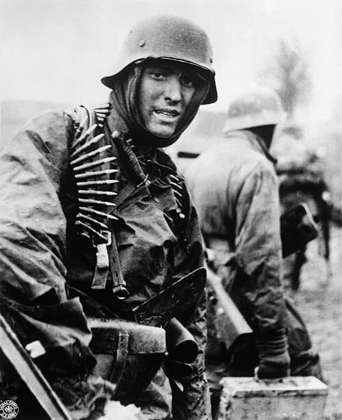 Duitse soldaat draagt munitiekisten tijdens het Ardennenoffensief, december 1944, bij Poteau na gevechten tegen U.S. 14th Cavalry.