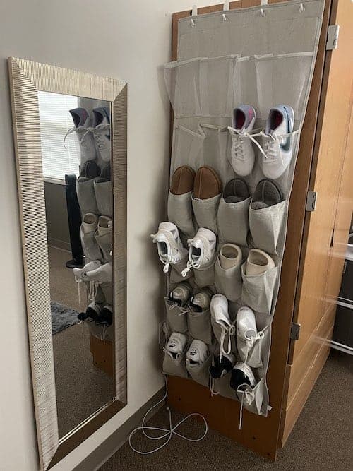 A hanging shoe organizer hooked onto a college dorm closet