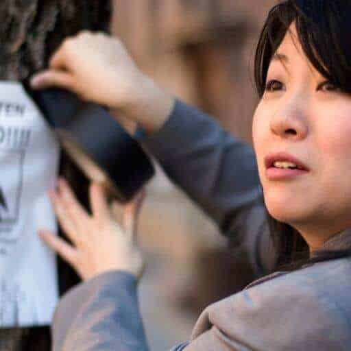 Asian woman hanging up a lost cat poster
