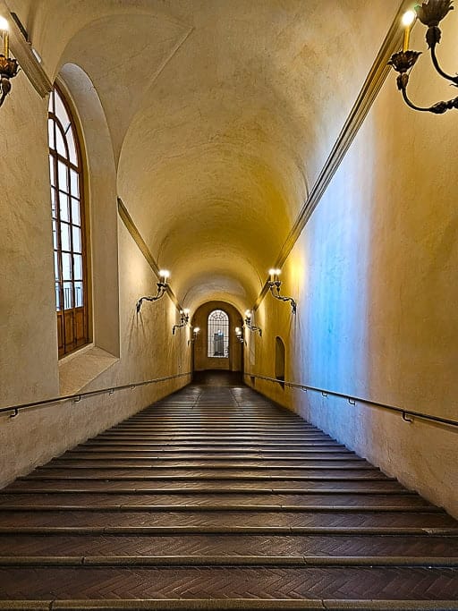 Historic staircase inside Palazzo d’Accursio in Bologna, designed for horse riders with elegant lighting.