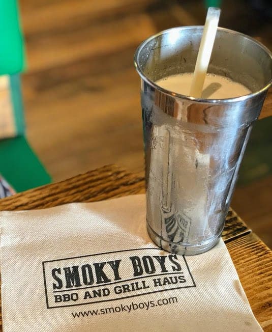 A milkshake on top of a Smoky Boys napkin on a wooden table