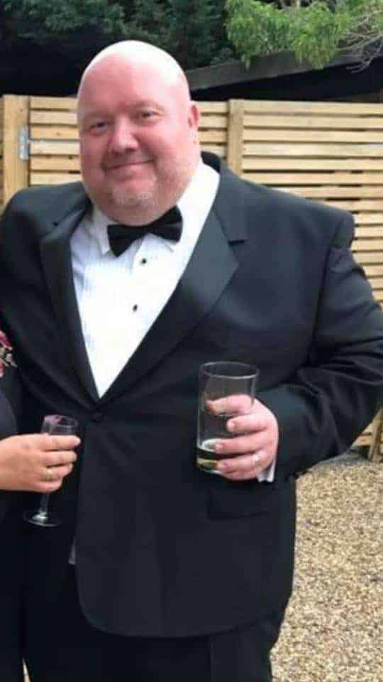 Adam wearing a black suit and a white shirt