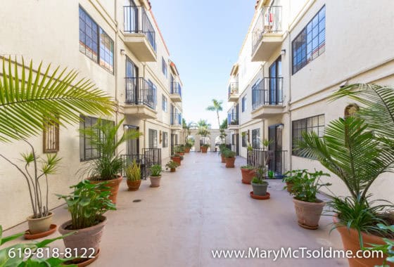 Modern Mediterranean-style apartment courtyard at 4205 Ohio Street with symmetrical balconies and large potted tropical plants.