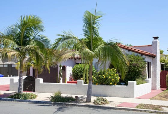 Spanish-style home with white stucco walls, a red clay tile roof, and palm trees at 3221 McKinley Street.