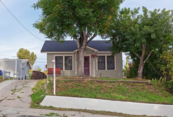 South Park home at 1739 31st Street features light sage siding, a gabled entryway with a red front door, and a shaded front yard with a mature tree.
