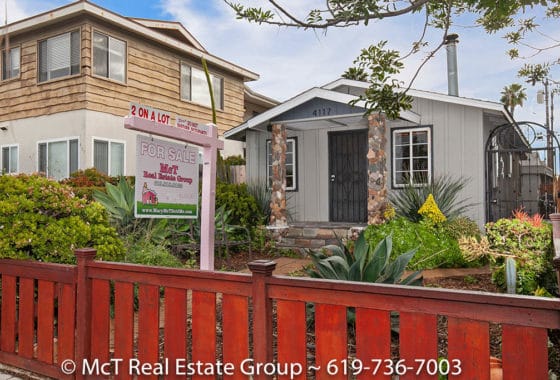 Charming cottage at 4117 33rd Street in North Park showcasing a rustic wood fence, stone-pillared entryway, and lush, drought-tolerant landscaping.