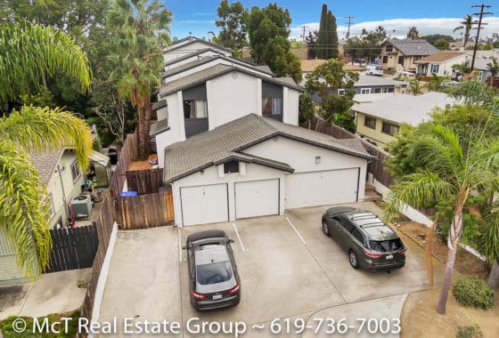 Aerial view of a multi-unit residential complex featuring white stucco exteriors, dark trim, and multiple garage bays at 3711 Louisiana Street in North Park.