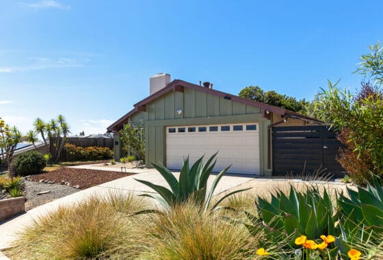 Single-story home exterior featuring a green facade, two-car garage, and desert landscaping with agave plants at 870 Marjorie Drive in Halecrest Heights.