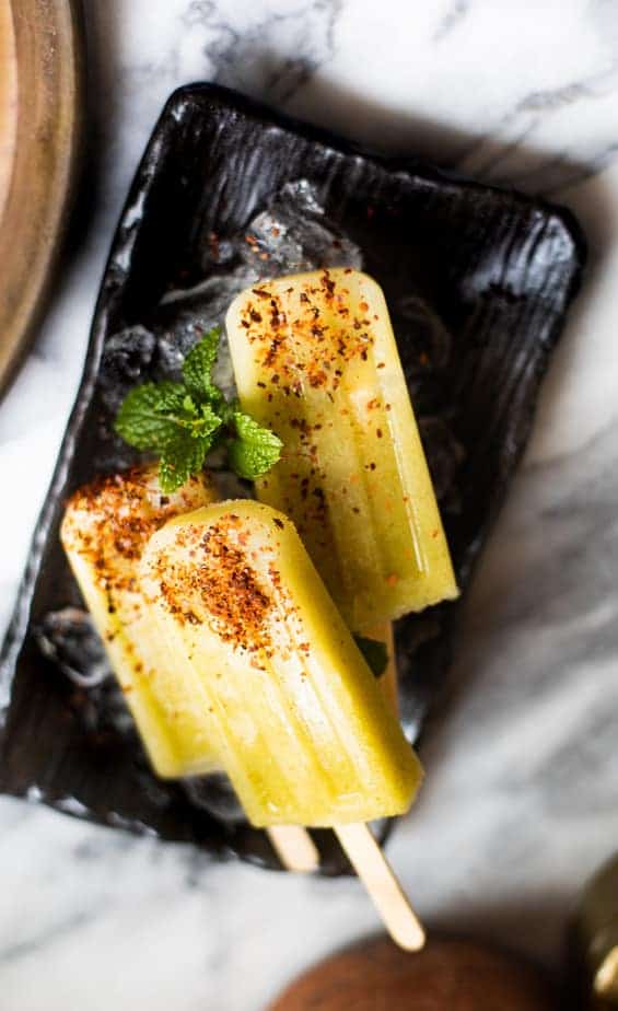 Green mango popsicles sprinkled with Aleppo pepper on a rectangular plate