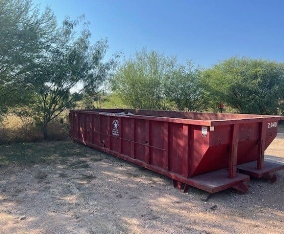 Large orange local dumpster rental filled with construction debris.