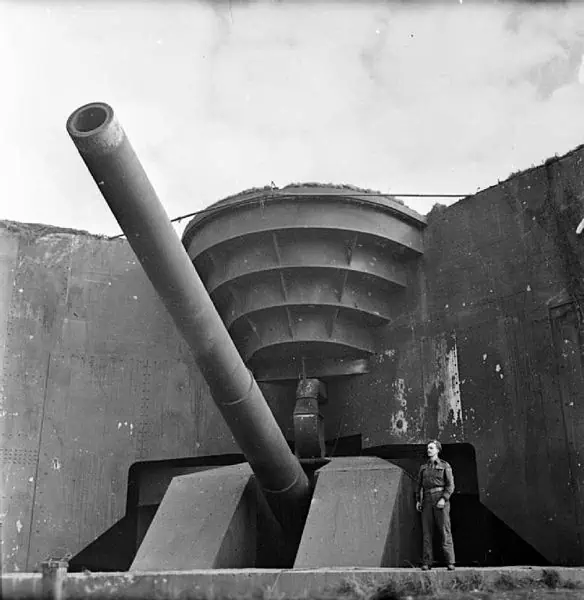 Een Canadese soldaat poseert bij een Duits kustgeschut, buitgemaakt door de Canadezen bij Cap Gris Nez op 1 oktober 1944.