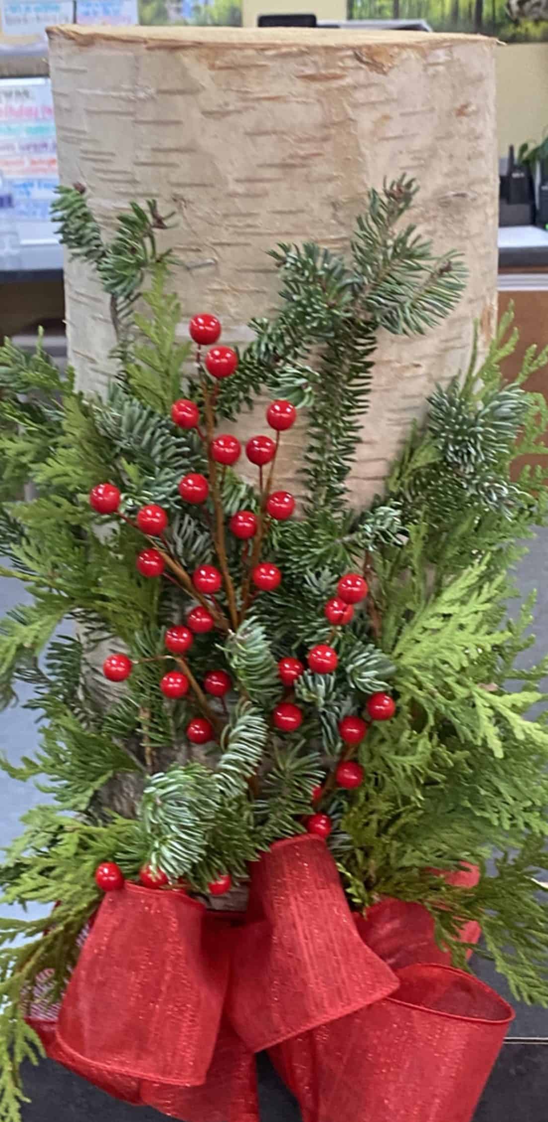 Festive holiday decoration with red berries, green pine branches, and a red bow.
