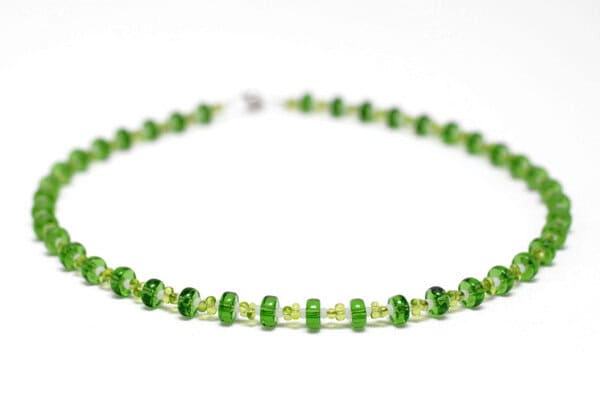 Zarte grüne Halskette mit limettengrünen Glasperlen auf hellem Hintergrund