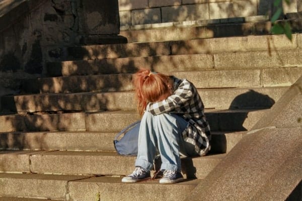A girl sitting on the glass steps of a building.