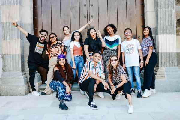 group of happy young people posing by wooden gate