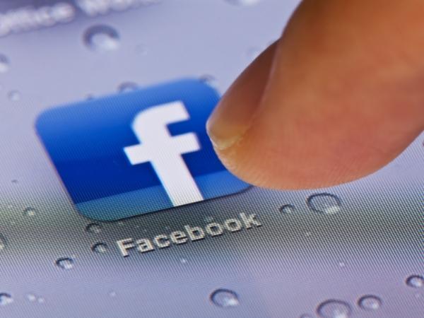finger pressing the Facebook icon on a phone